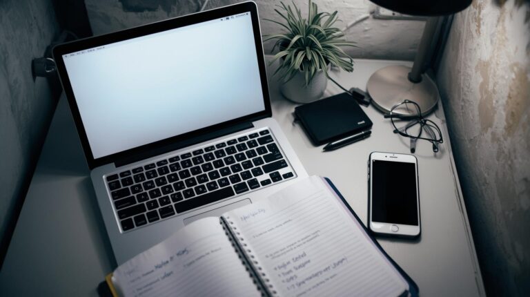 Laptop with notebook and phone setup for implementing crisis legal team workflow guide and response protocols